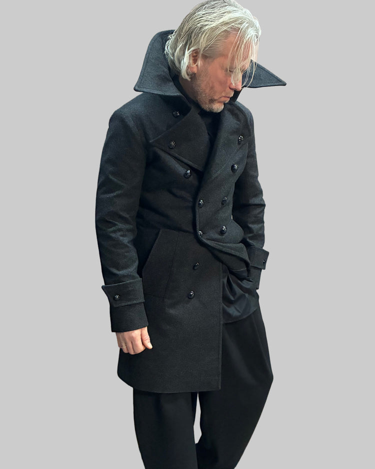 Person wearing a long grey coat in a dynamic position.