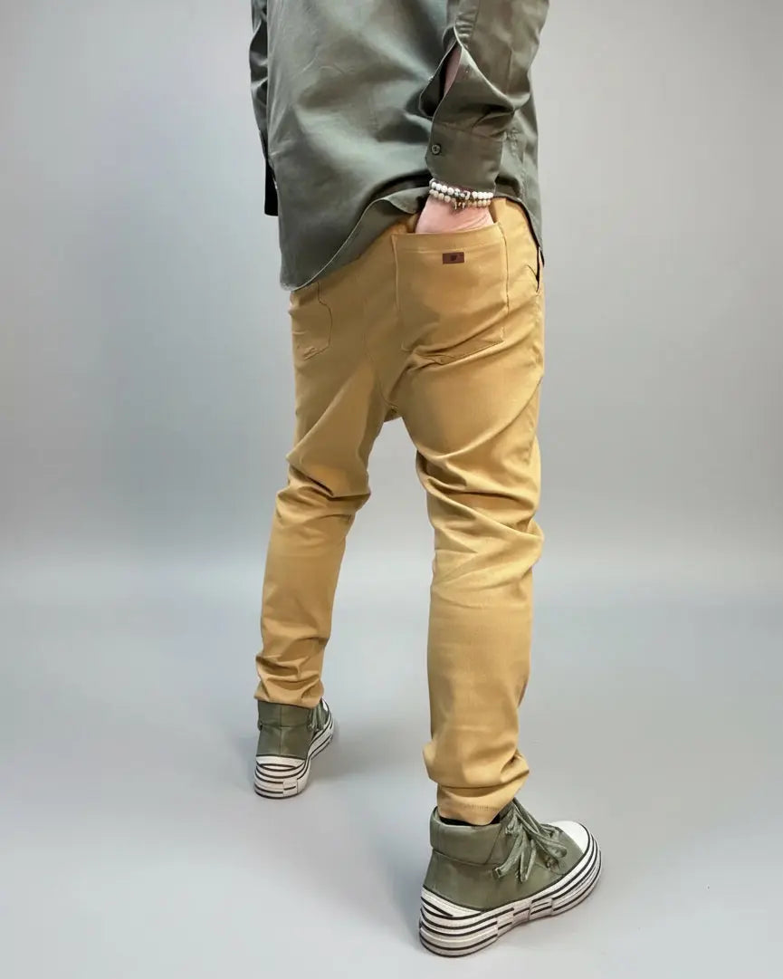 Person wearing beige pants and green shoes in an urban setting showing his hand in the back pocket.