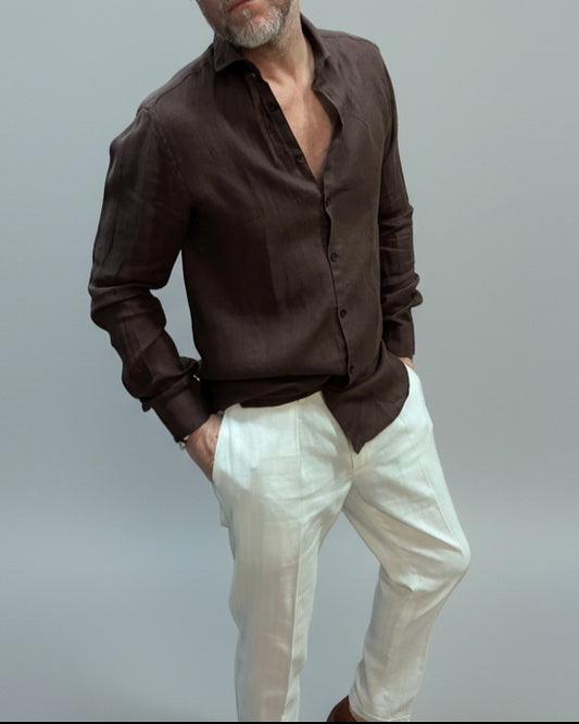 Model wearing a brown button-up shirt and white pants against light grey backdrop