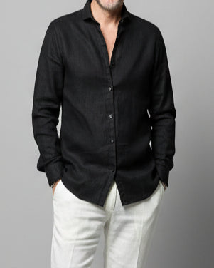 Model wearing a black shirt and white pants in front of light grey backdrop