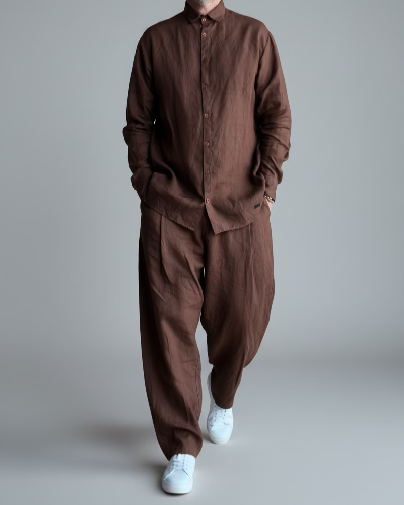 Man in a brown outfit standing against light grey backdrop