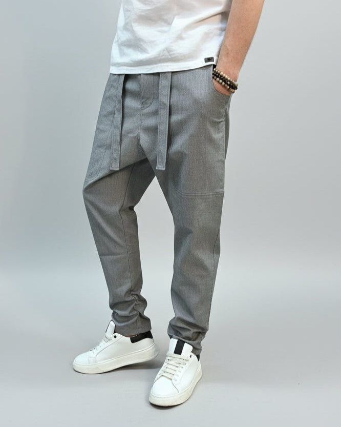 Person wearing grey dogtooth pants and white T-shirt and white sneakers on a gray floor.