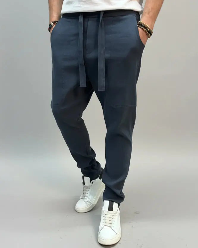 Person wearing a white shirt and blue pants standing on a gray floor with a brown fabric draped over them.