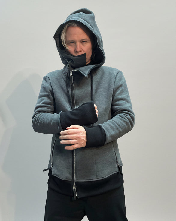 Person wearing a gray hoodie on a light grey background showing his fists.
