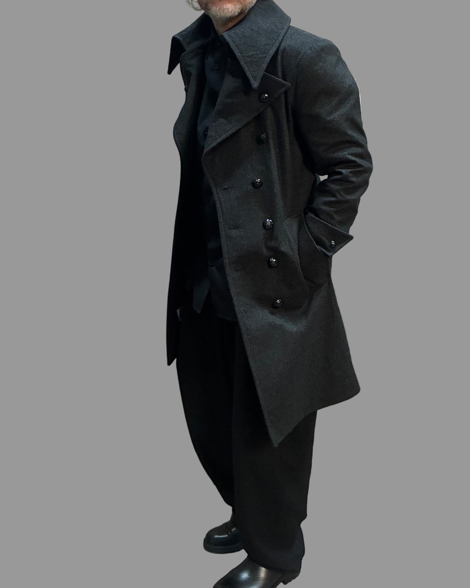 Person wearing a long grey coat in a dynamic position.