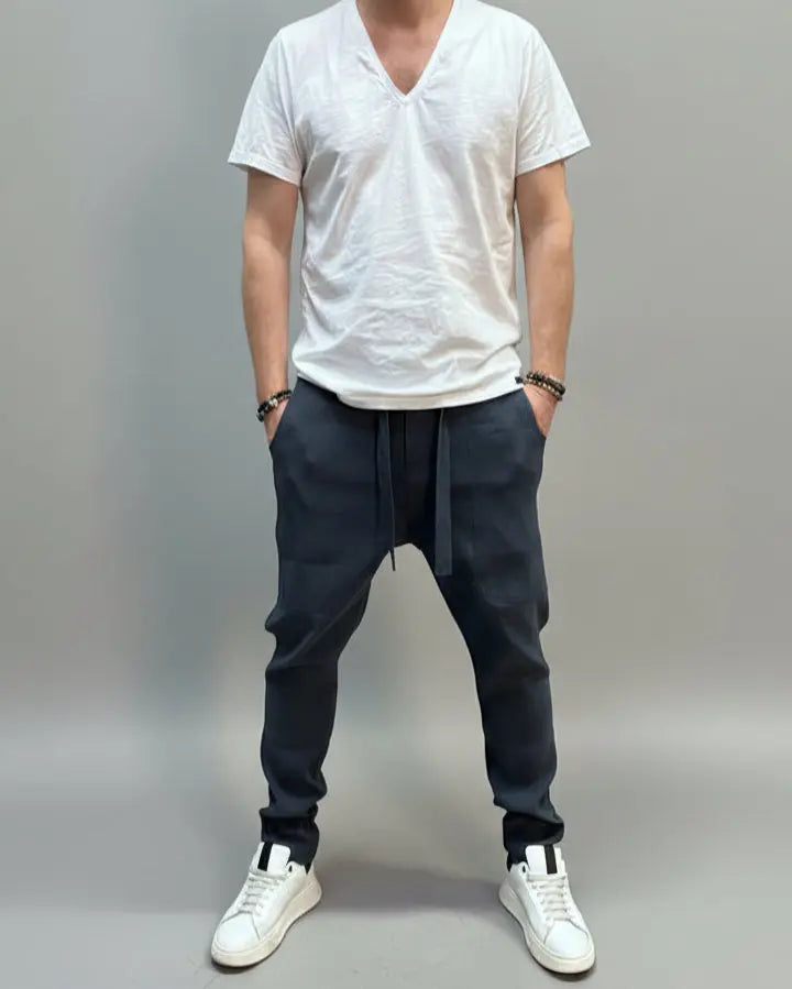 Person wearing a white shirt and blue pants standing on a gray floor with a brown fabric draped over them.