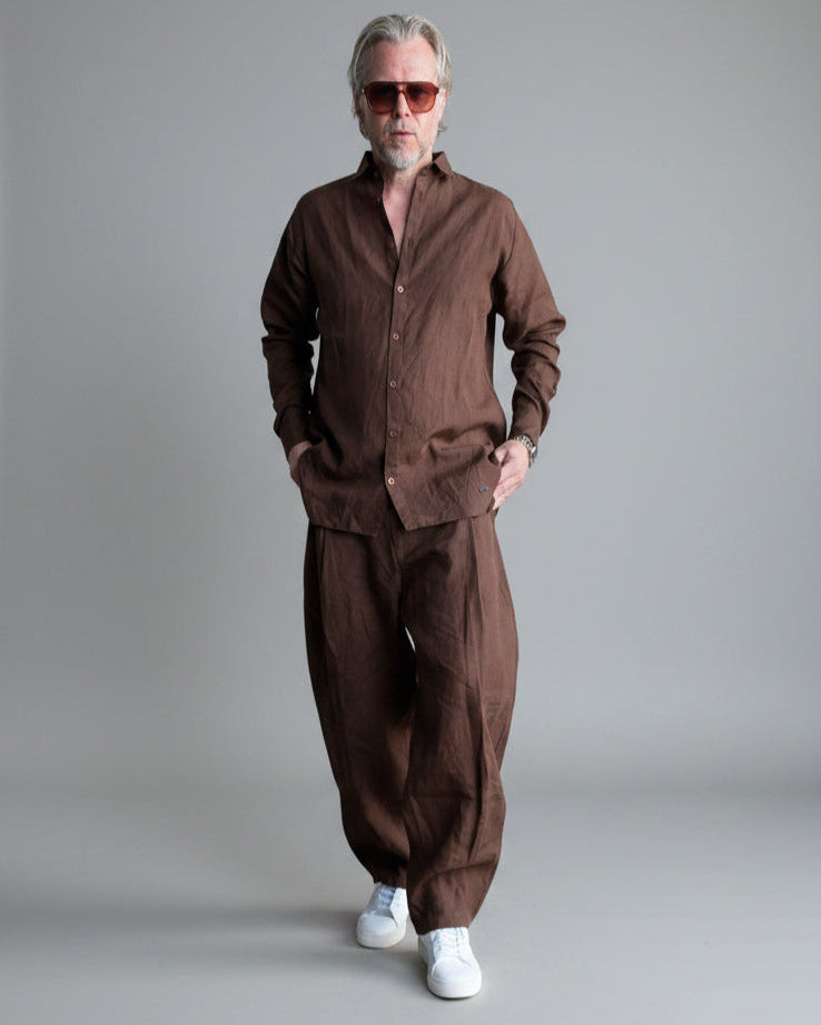 Man in a brown outfit standing against light grey backdrop