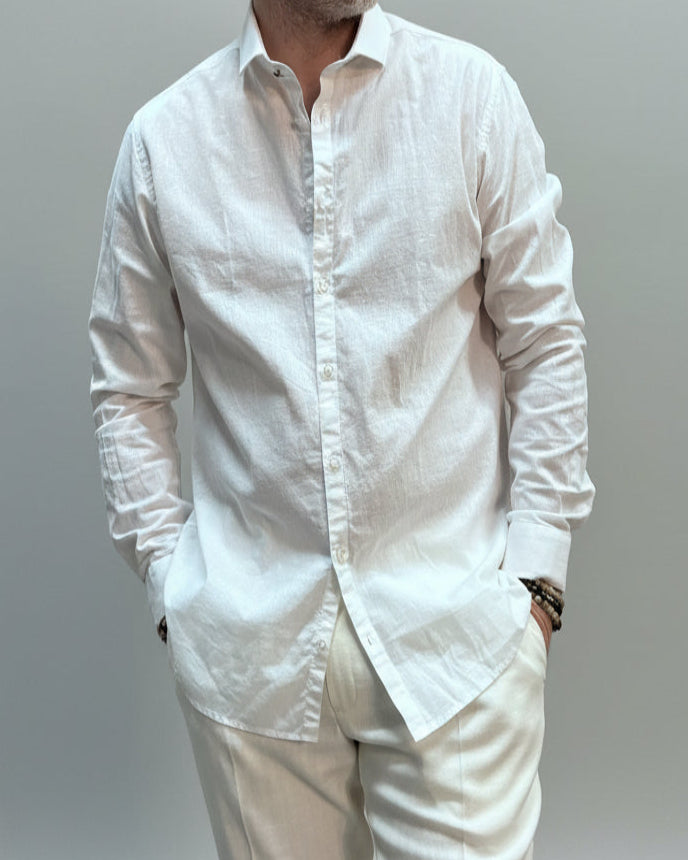 Model  wearing a white shirt and white pants in front of light grey backdrop