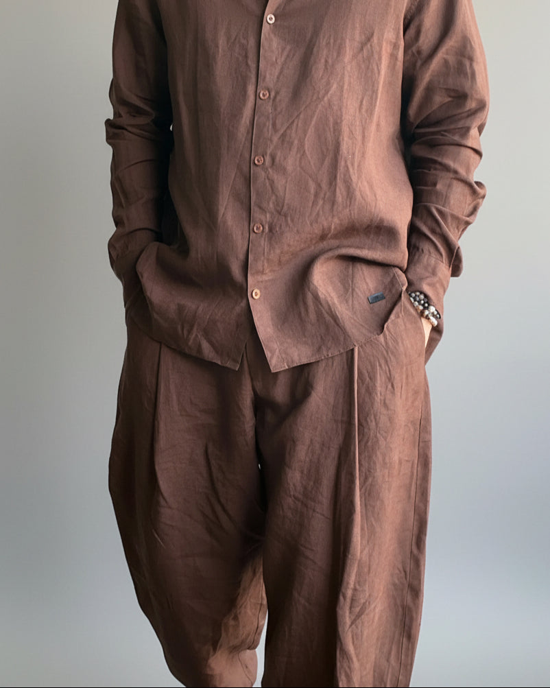 Man in a brown outfit standing against light grey backdrop