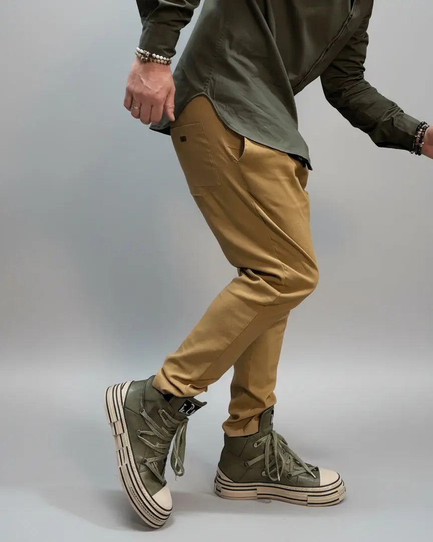 Person wearing green shirt, beige pants, and green high-top sneakers in an urban setting in a dynamic position