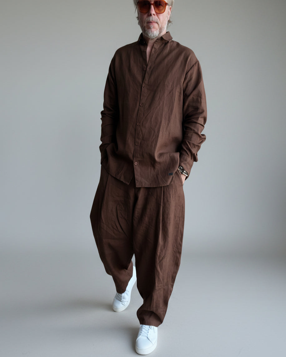 Man in a brown outfit standing against light grey backdrop
