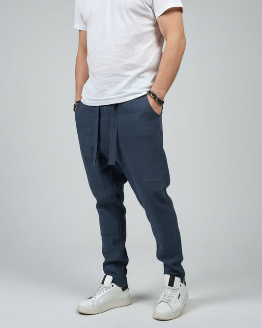 Person wearing a white shirt and blue pants standing on a gray floor with a brown fabric draped over them.