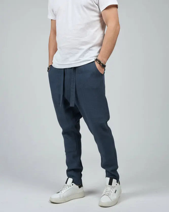 Person wearing a white shirt and blue pants standing on a gray floor with a brown fabric draped over them.