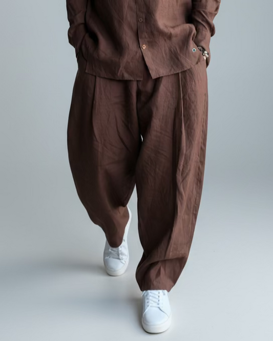 Man in a brown outfit standing against light grey backdrop