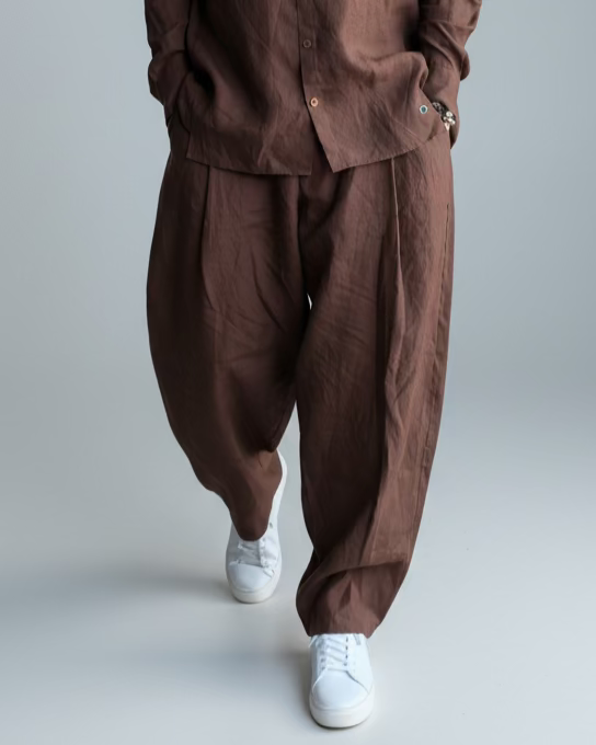 Man in a brown outfit standing against light grey backdrop
