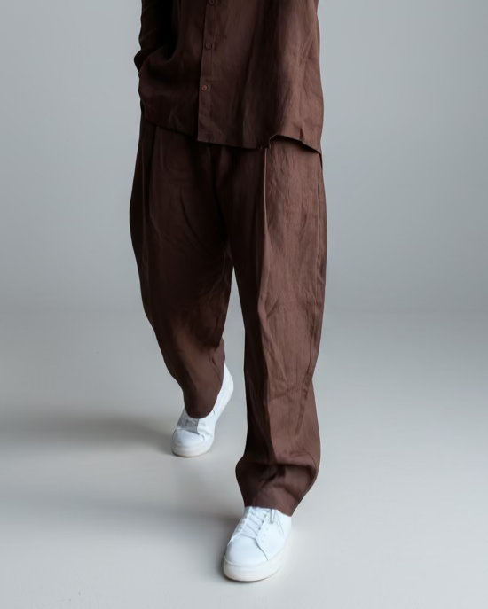 Man in a brown outfit standing against light grey backdrop