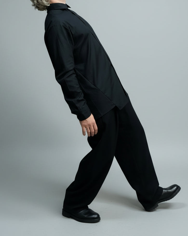 Person wearing a black outfit in a minimal indoor setting in a dynamic pose