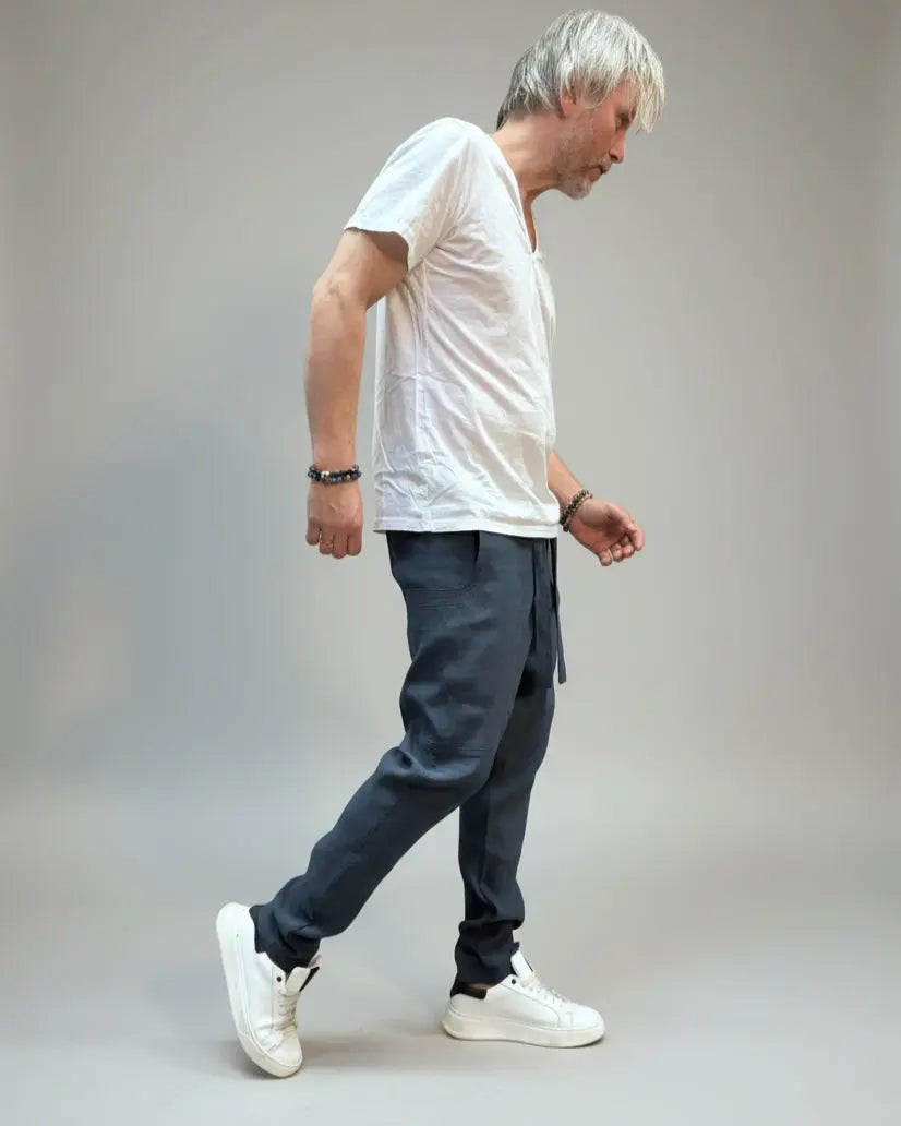 Person wearing a white T-shirt and blue pants standing on a gray floor with a brown fabric draped over them.