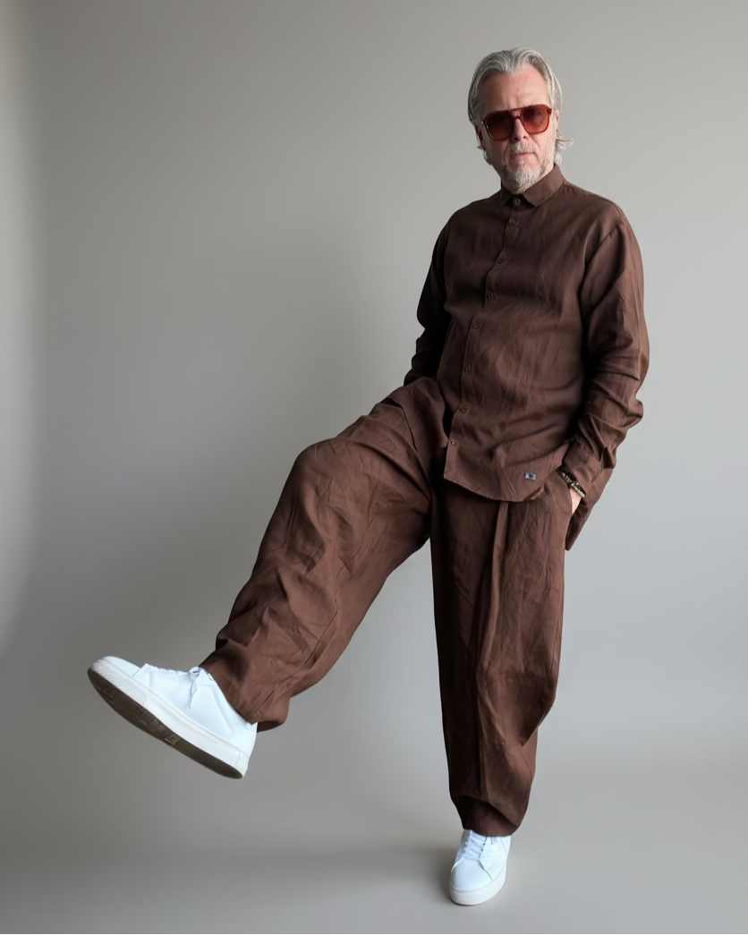 Man in a brown outfit standing against light grey backdrop