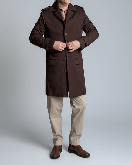 MODEL STANDING IN FRONT OF L. GREY BACKDROP WEARING A BROWN TRENCH COAT