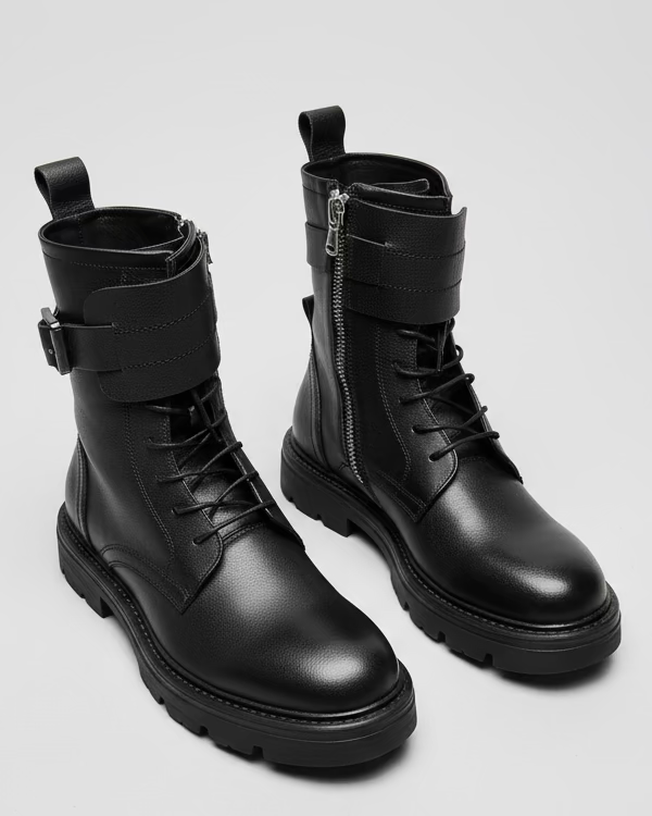 Pair of black leather boots with zippers on a light grey backdrop
