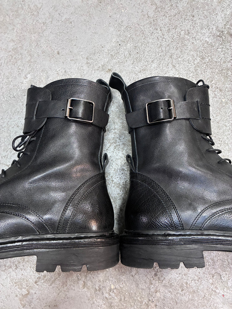 Photo of pair of combat boots lied spread out on grey backdrop