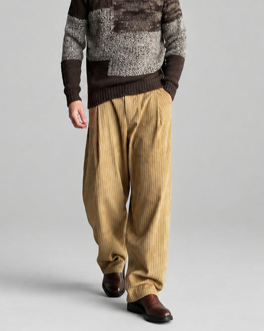 Model in dark beige corduroy pants and brown grey beige patchwork wool roll-neck sweater.