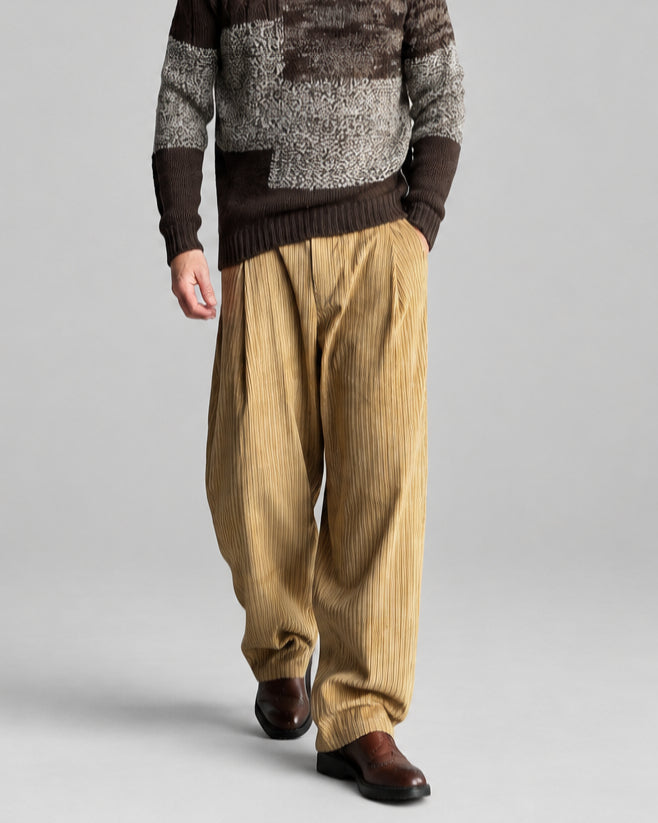 Model in dark beige corduroy pants and brown grey beige patchwork wool roll-neck sweater.